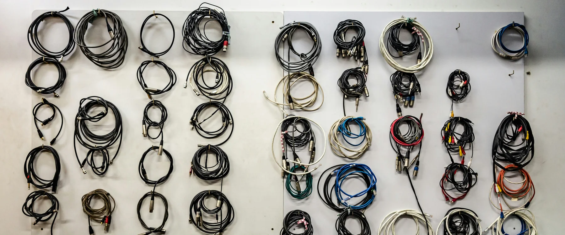 Coiled cables with assorted audio, video and signal connectors hanging on a wall display