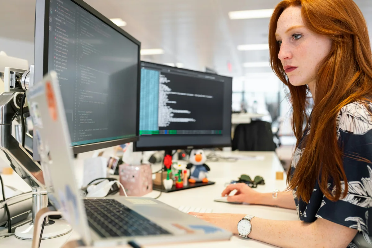 Woman working at a computer workstation with multiple monitors