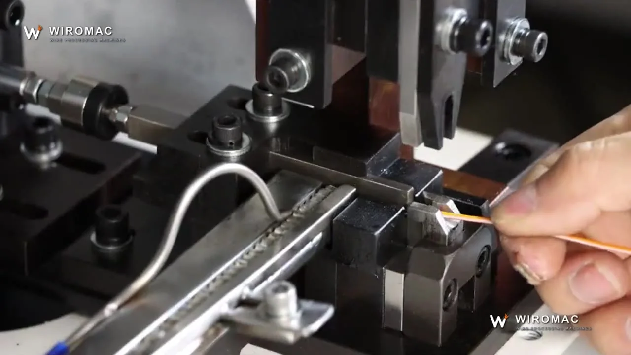Bowl-fed loose terminals onto a bench press — pre-insulated fork terminal held up after the stroke.