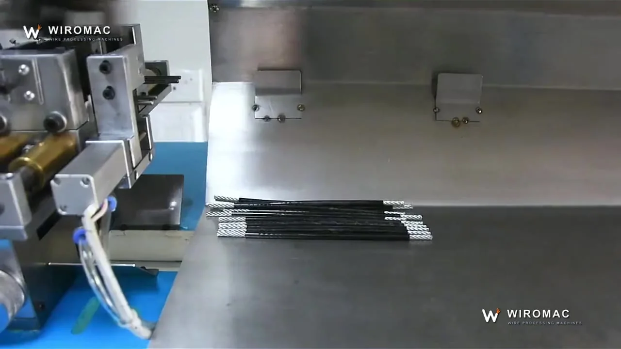 Multi-core sheathed cable on a bench machine — jacket and cores stripped, bundle collected.