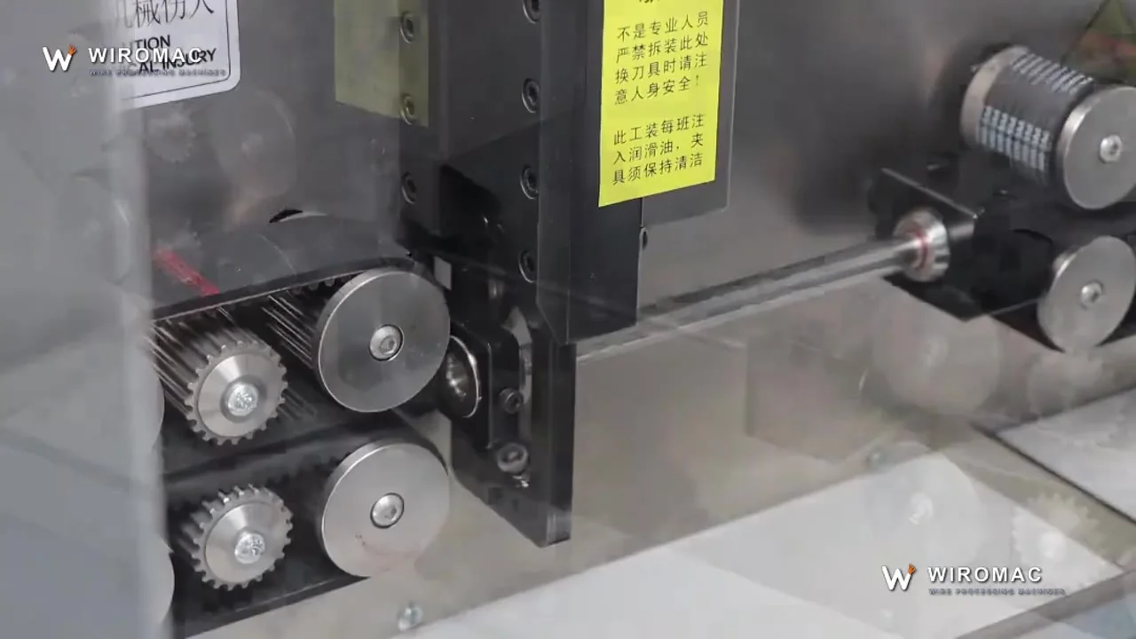 Eight-wheel belt drive on a servo cut-and-strip head — wire held flat, not pinched.